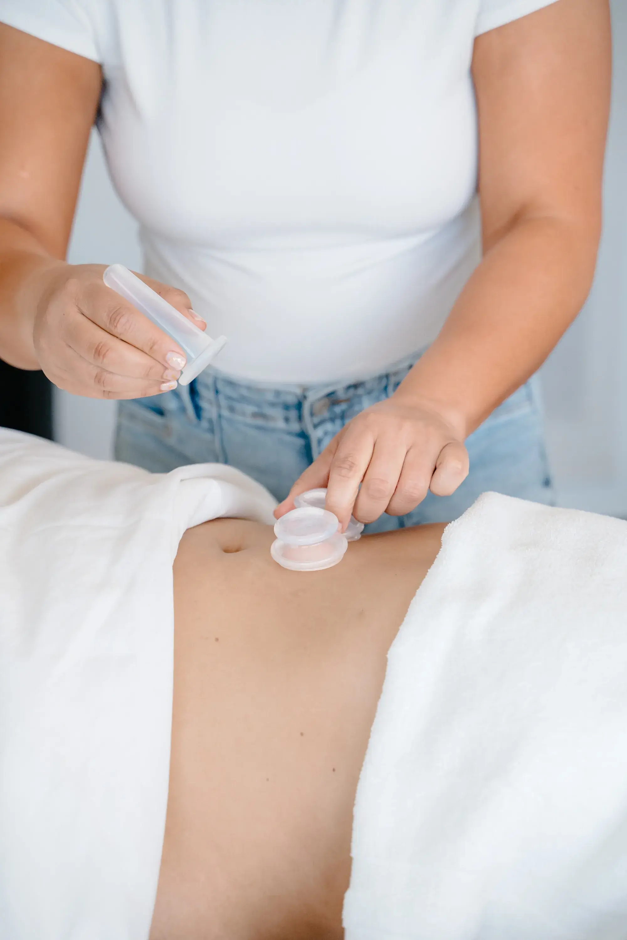 Flat hands resting lightly on the abdomen during post-operative lymphatic drainage at Renu