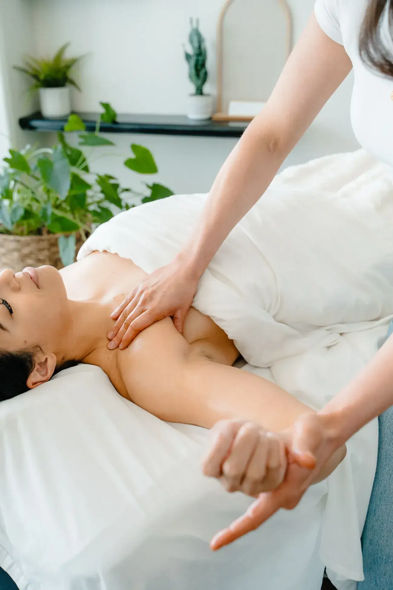 A therapist’s hands working along a client’s neck and shoulder during lymphatic drainage